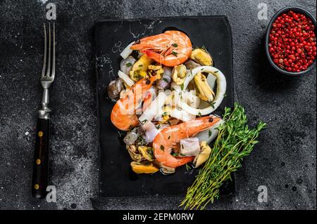 Frisch gemischter Meeresfrüchte-Cocktail mit Garnelen, Garnelen, Muscheln, Tintenfischen und Oktopus. Schwarzer Hintergrund. Draufsicht Stockfoto