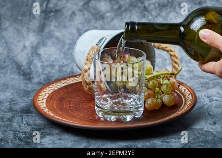 Kleine Eimer Trauben in Keramikplatte und Hand Gießen Wein Stockfoto