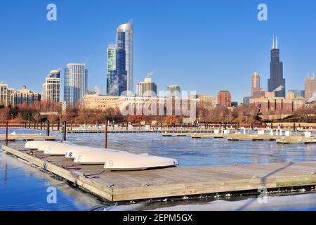 Chicago, Illinois, USA. Umgedrehte Ruderboote auf einem Dock bilden einen Kontrast in einem gefrorenen Hafen von Burnham. Stockfoto