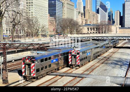 Chicago, Illinois, USA. Ein eingehender Metra Pendlerzug, der entlang einer elektrifizierten Strecke an einem stehenden Zug an der VanBuren Street Station vorbeifährt. Stockfoto