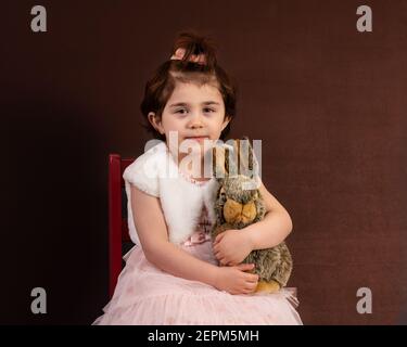 Lächelndes junges Mädchen hält Plüsch Häschen isoliert auf schwarz. Stockfoto