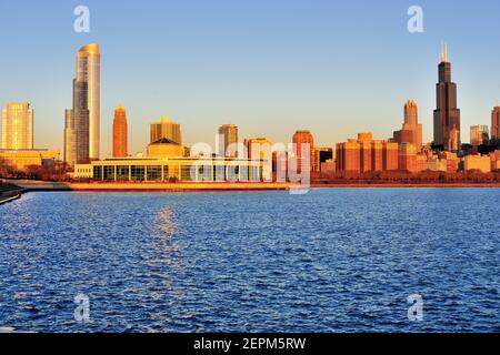 Chicago, Illinois, USA. Die aufgehende Sonne über dem Lake Michigan spiegelt sich vom Adler Planetarium und einem Teil der Skyline von South Loop wider. Stockfoto