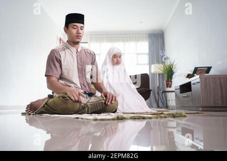 asiatische muslimische Mann und Frau beten jamaah zusammen zu Hause Stockfoto
