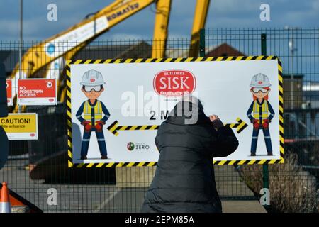 Dublin, Irland. Februar 2021, 26th. Eine Frau geht an einem sozialen Distanzierungsschild von 2m in Howth Harbour vorbei. Kredit: SOPA Images Limited/Alamy Live Nachrichten Stockfoto