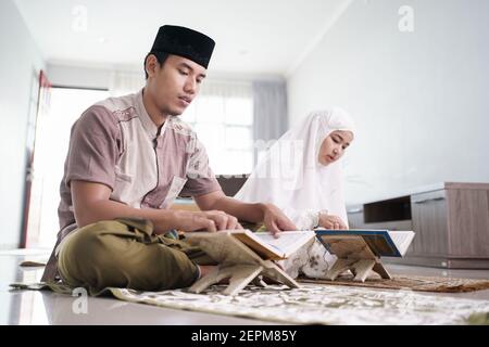 Asiatische muslimische Mann Lehre Frau Lesen Koran oder Koran im Wohnzimmer. muslim Paar zu Hause beten Stockfoto