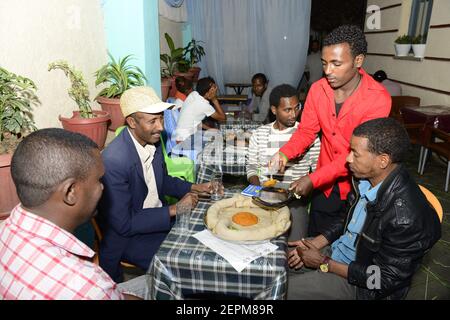 Äthiopier genießen ein traditionelles Injera-Gericht mit verschiedenen Gemüsesorten und Saucen. Stockfoto