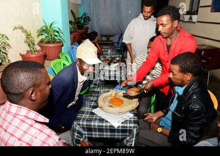 Äthiopier genießen ein traditionelles Injera-Gericht mit verschiedenen Gemüsesorten und Saucen. Stockfoto