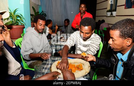 Äthiopier genießen ein traditionelles Injera-Gericht mit verschiedenen Gemüsesorten und Saucen. Stockfoto