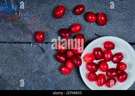 Ein Teller mit roten Kornelbeeren auf blauem Hintergrund Stockfoto