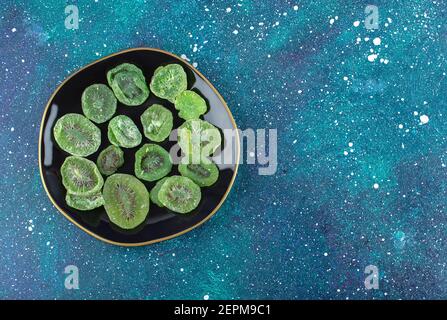 Draufsicht auf trockene Kiwi-Scheiben auf schwarzem Teller Stockfoto
