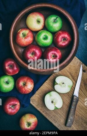 Malus domestica. Grüne und rote Äpfel in einer Schüssel und auf einem Holzbrett schneiden Stockfoto