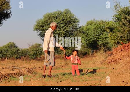Ein schönes kleines indisches Kind nimmt einen Stachel von seinem Großvater innerhalb der Farm, Indien. Konzept für Indiens Vergangenheit lächelndes Kind, Kindheit, Kind Stockfoto