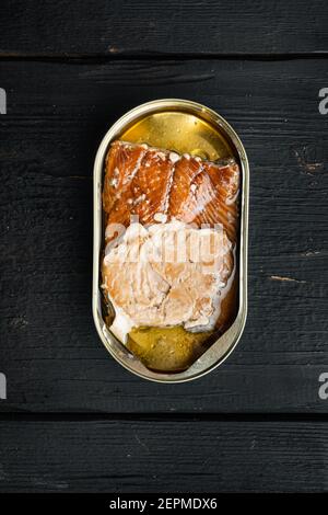 Wild Alaska Lachs Räucherfischset in Dosen, in Blechdose, auf schwarzem Holztisch Hintergrund, Draufsicht flach liegend Stockfoto