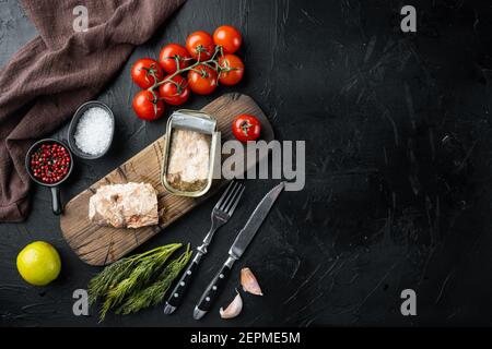 Dosen Wild Alaska Lachs Set, auf Holzschneidebrett, auf schwarzem Hintergrund mit Kräutern und Zutaten, Draufsicht flach legen, mit Copyspace und Platz für Stockfoto