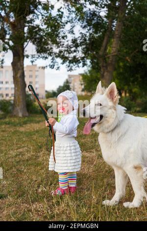 Junge schöne Mädchen mit einem weißen Schweizer Schäferhund spielt auf Der Rasen zur Tageszeit Stockfoto