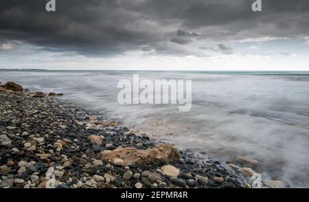 Seeschiffe planschen mit Steinen an die Küste gegen den stürmischen dramatischen Wolkenhimmel. Winterzeit, Limassol zypern Stockfoto