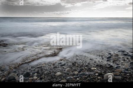 Seeschiffe planschen mit Steinen an die Küste gegen den stürmischen dramatischen Wolkenhimmel. Winterzeit, Limassol zypern Stockfoto