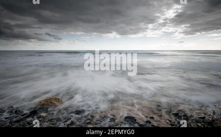 Seeschiffe planschen mit Steinen an die Küste gegen den stürmischen dramatischen Wolkenhimmel. Winterzeit, Limassol zypern Stockfoto