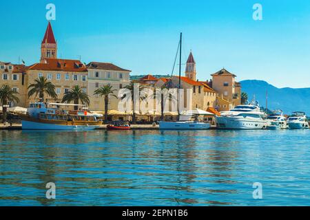 Schöne Aussicht mit Luxusyachten und Booten im touristischen Hafen. Beliebte Uferpromenade mit Palmen und Straßencafés, Trogir, Dalmatien, Kroatien Stockfoto