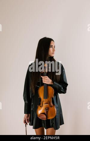 Geigerin mit Musikinstrument stehend und nachdenklich wegschauend Stockfoto