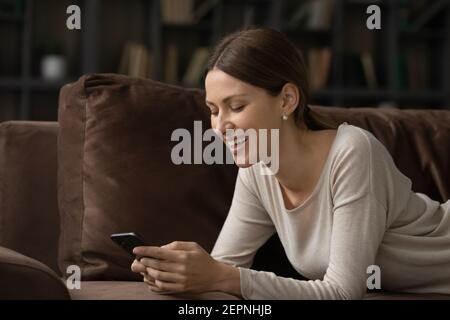 Glückliche Frau entspannen auf Couch SMS online auf Zelle Stockfoto