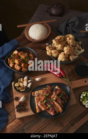 Mala Tofu und yuxiang, chinesische vegane Gerichte, begleitet von einer Schüssel mit Reis, Blumenkohl, Sojasauce und einer japanischen Teekanne auf einer hölzernen Tischdeko Stockfoto