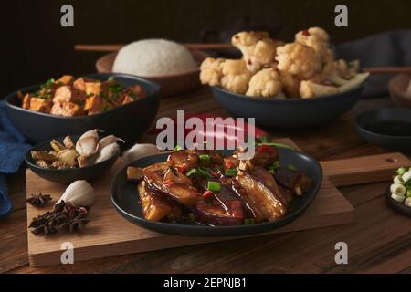 Mala Tofu und yuxiang, chinesische vegane Gerichte, begleitet von einer Schüssel mit Reis, Blumenkohl, Sojasauce und einer japanischen Teekanne auf einer hölzernen Tischdeko Stockfoto