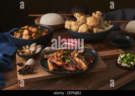 Mala Tofu und yuxiang, chinesische vegane Gerichte, begleitet von einer Schüssel mit Reis, Blumenkohl, Sojasauce und einer japanischen Teekanne auf einer hölzernen Tischdeko Stockfoto