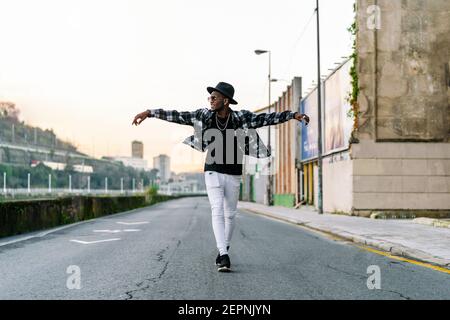 Junge afroamerikanische Männchen in trendigen tragen und Kette suchen Weg auf städtischer Asphaltstraße Stockfoto