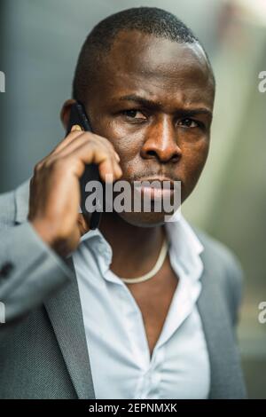 Erwachsene afroamerikanische Geschäftsmann in stilvollem Anzug reden auf Handy Beim Blick in die Stadt Stockfoto