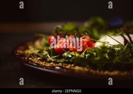 Nahaufnahme des leckeren Burrata-Käses auf kalten Tomaten Sahne mit Rucola Blätter und Kirschtomaten mit Trüffeln und Erdnüsse Stockfoto