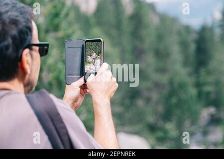 Rückansicht der Ernte anonymen männlichen Trekker in Sonnenbrillen nehmen Foto der Geliebten auf dem Handy während der Reise Stockfoto