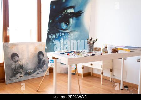 Art Studio Interieur mit Sammlung von gemalten Bildern und Farbe Bürsten in Glas auf Tisch bei Tageslicht Stockfoto