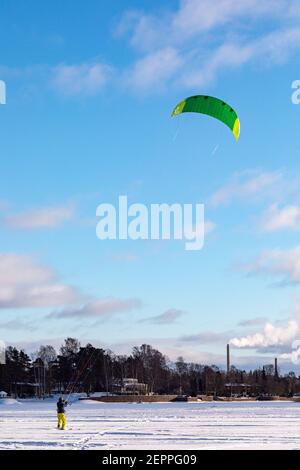 Person Snowkiten oder Kiteskifahren auf gefrorener Laajalahti Bucht im Munkkiniemi Bezirk von Helsinki, Finnland Stockfoto