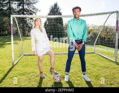 Fußball-Fashion-Geschichte mit einem schwarzen männlichen Modell und Blondine Chinesische weibliche Modell erzielte ein Tor auf einem Fußballplatz Stockfoto