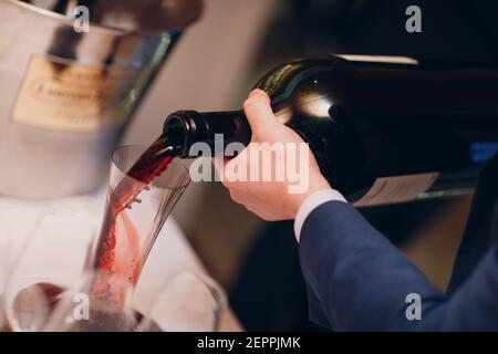 Der Kellner gießt erlesenen Rotwein in die Dekanter auf dem Tisch im Restaurant. Stockfoto