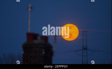 London, Großbritannien. 27. Februar 2021. Voller Schneemond erhebt sich zwischen einem Hauskamin und einem Mast im Süden Londons. Kredit: Malcolm Park/Alamy Stockfoto