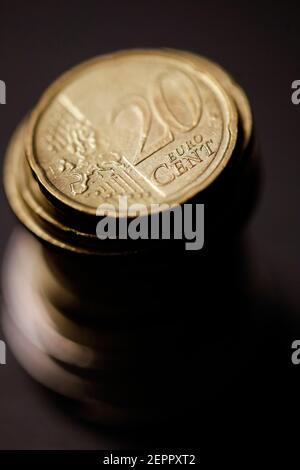 Geringe Schärfentiefe (selektiver Fokus) und Makrobild mit einer 20-Cent-Metallmünze in der Nähe anderer Euro-Münzen auf schwarzem Hintergrund. Stockfoto