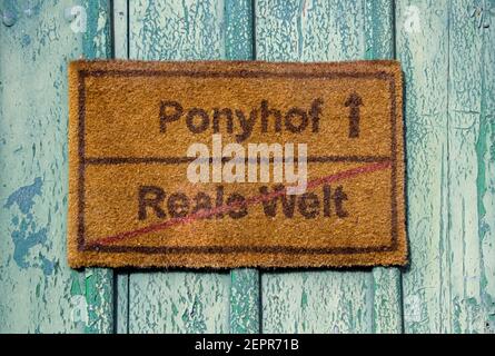 Straßenschild auf deutsch mit 'Ponyhof' und 'reale Welt' spielen Mit dem deutschen Äquivalent zum Sprichwort "Live ist nein Sonntagsschule Picknick' Stockfoto