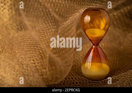 Braune Sanduhr auf Gold Wabengitter Hintergrund. Das Konzept der Vergänglichkeit der ablaufenden Zeit ist Wert. Nahaufnahme mit Kopierbereich. Stockfoto