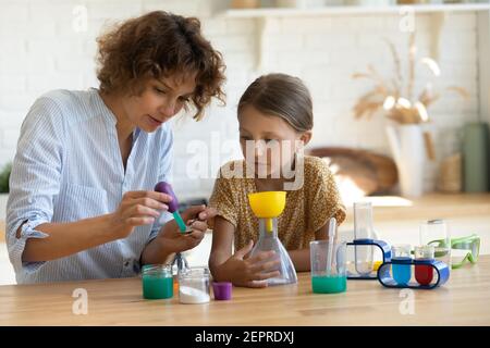 Kleines Mädchen beobachten ältere Schwester mit Chemie-Set für Kinder Stockfoto