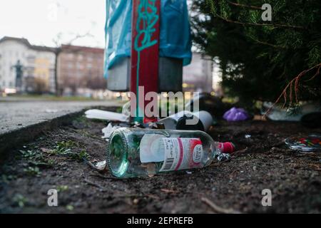 Berlin, Deutschland. Februar 2021, 27th. Eine leere Weinflasche liegt auf dem Boden vor einem überfließenden Abfalleimer im Park nahe dem Planetarium. Quelle: Gerald Matzka/dpa-Zentralbild/ZB/dpa/Alamy Live News Stockfoto