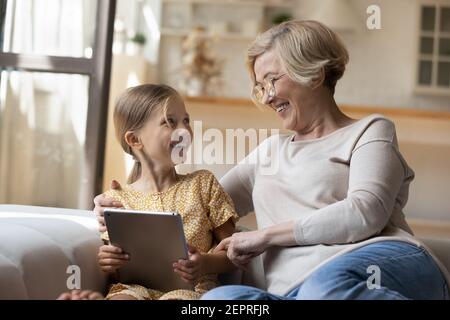 Lachend Oma Umarmung kleine Enkelin diskutieren lustige Foto auf Pad Stockfoto