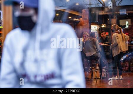 Athen, Usa. Februar 2021, 27th. Gavin Lloyd, 24, aus Athen, Ohio wartet auf die Gelegenheit, die Pigskin Bar and Grille zu betreten. Während das Wetter in Ohio aufwärmt Studenten von der Ohio University Kopf zur Court Street, um an Bars zu sozialisieren. Die Impfstoffverteilung ist in Ohio noch im Gange, aber für Studenten, die nicht mit vielen Personen außerhalb ihrer Kohorte interagieren, hat die Bedrohung durch die Coronavirus-Krankheit (COVID-19) sie nicht davon abgehalten, eine Nacht in der Stadt zu verbringen. Kredit: SOPA Images Limited/Alamy Live Nachrichten Stockfoto