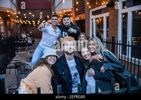 Athen, Usa. Februar 2021, 27th. Eine Gruppe von Freunden posieren für ein Foto auf der Terrasse vor Courtside Pizza. Während das Wetter in Ohio aufwärmt Studenten von der Ohio University Kopf zur Court Street, um an Bars zu sozialisieren. Die Impfstoffverteilung ist in Ohio noch im Gange, aber für Studenten, die nicht mit vielen Personen außerhalb ihrer Kohorte interagieren, hat die Bedrohung durch die Coronavirus-Krankheit (COVID-19) sie nicht davon abgehalten, eine Nacht in der Stadt zu verbringen. Kredit: SOPA Images Limited/Alamy Live Nachrichten Stockfoto