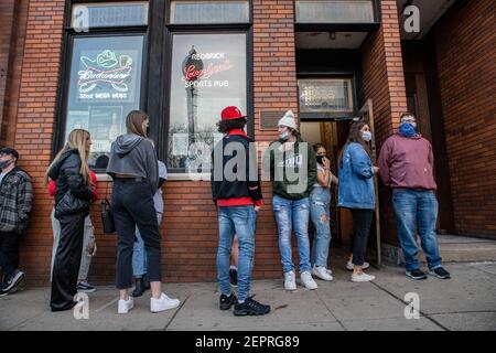 Athen, Usa. Februar 2021, 27th. Die Schüler warten darauf, die Red Brick Tavern zu betreten. Während das Wetter in Ohio aufwärmt Studenten von der Ohio University Kopf zur Court Street, um an Bars zu sozialisieren. Die Impfstoffverteilung ist in Ohio noch im Gange, aber für Studenten, die nicht mit vielen Personen außerhalb ihrer Kohorte interagieren, hat die Bedrohung durch die Coronavirus-Krankheit (COVID-19) sie nicht davon abgehalten, eine Nacht in der Stadt zu verbringen. Kredit: SOPA Images Limited/Alamy Live Nachrichten Stockfoto