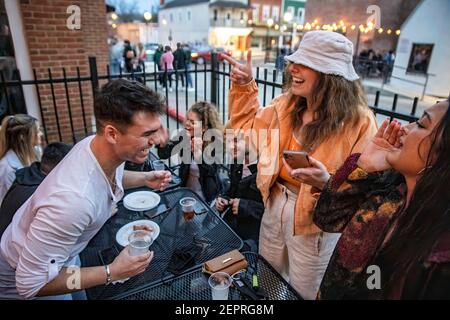 Athen, Usa. Februar 2021, 27th. Dominick Prince (links), 22, aus Athen, Ohio genießt mit seinen Freunden auf der Terrasse vor der Courtside Pizza. Während das Wetter in Ohio aufwärmt Studenten von der Ohio University Kopf zur Court Street, um an Bars zu sozialisieren. Die Impfstoffverteilung ist in Ohio noch im Gange, aber für Studenten, die nicht mit vielen Personen außerhalb ihrer Kohorte interagieren, hat die Bedrohung durch die Coronavirus-Krankheit (COVID-19) sie nicht davon abgehalten, eine Nacht in der Stadt zu verbringen. Kredit: SOPA Images Limited/Alamy Live Nachrichten Stockfoto