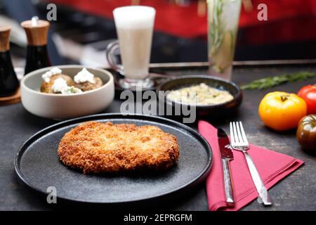 Schweinekotelett in einer knusprigen Panko-Beschichtung gebraten. Gericht auf einem dunklen Teller. Menüvorschlag. Stockfoto