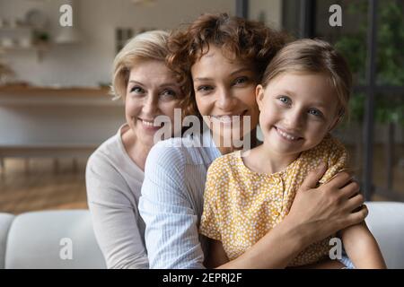 Generationenfamilie aus drei verschiedenen Frauen kuscheln auf dem Sofa Stockfoto