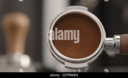 Slow-Motion-Mann-Show tamped frisch gemahlenen Kaffee in Portafilter, breites Foto Stockfoto